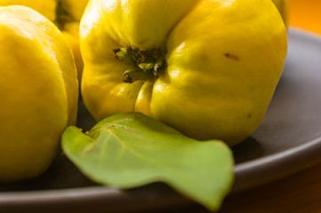 large yellow quince fruits on a ceramic plate, with anise, cinnamon, and walnuts