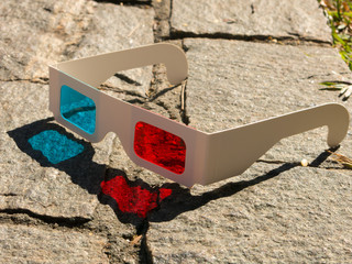 Red cyan stereophotography anaglyph 3D glasses on rocks ground pattern