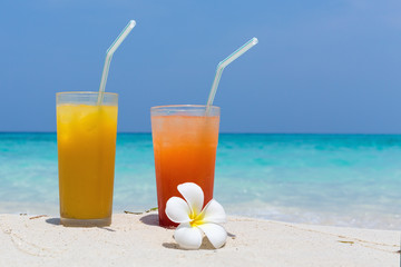 Cocktails in glass on white sandy beach