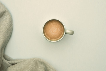 A cup of coffee with milk and a warm bedspread. Top view