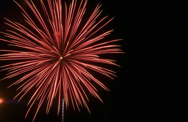 Large star burst mixture of red and white against a black sky on the Fourth of July