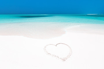 Fototapeta na wymiar Heart symbol drawing on white sandy beach
