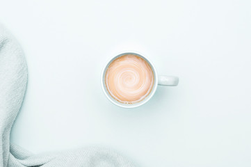 A cup of coffee with cream and a warm blanket. Cool background.