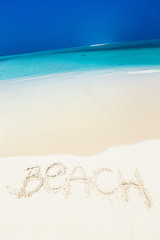 Inscription word BEACH on perfect tropical sandy beach