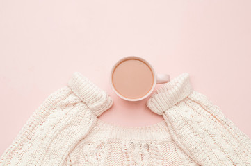 Cup of coffee with milk and a sweater on a pink background. Top view