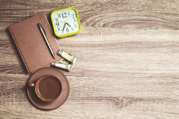Cup of coffee, notebook, pen, money and clock on wooden background. Top view