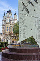 An old beautiful church behind monument to World War Two on background of blue sky. Religious...