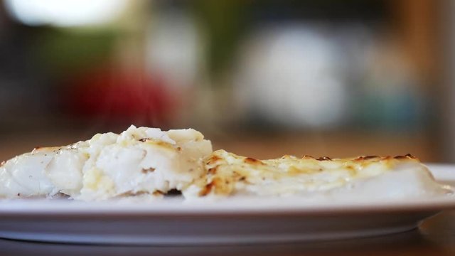Person places lemon on pollock dish, close up