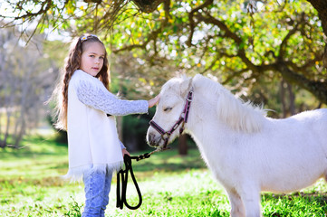 Cute little girl and pony in a beautiful park