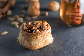 Closeup of birds nest baklava with almonds, cardamom and honey, angle view on black stone slate. Arabian dessert. Kadayif bulbul nest, (bulbul yuvasi), Turkish dessert.