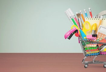 Colorful school supplies in shopping cart