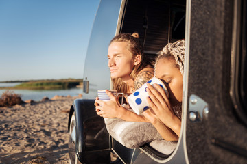 Morning coffee. Couple of good-looking travelers drinking morning coffee after night in mobile home