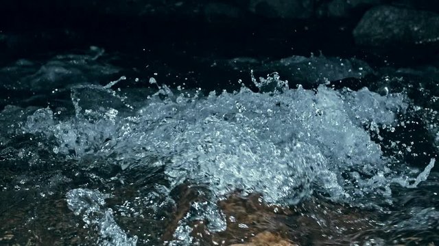 Slow motion of waves on dark water surface with play of flecks of bright light close up. Amazing dramatic natural background. Shooting with 180fps. Epic mystical and magic night view. Crystal clear