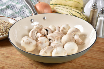 Fototapeta na wymiar Raw button mushrooms in a cast iron skillet