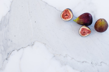 Whole and cut figs on marble kitchen bench top, flat lay with copy space