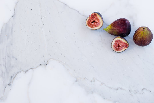 Whole and cut figs on marble kitchen bench top, flat lay with copy space