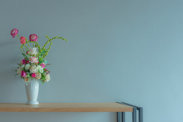 Flowers in vase on the table with light blue background wall.