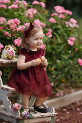 Little girl and decorated party with a cake in the flowers garden