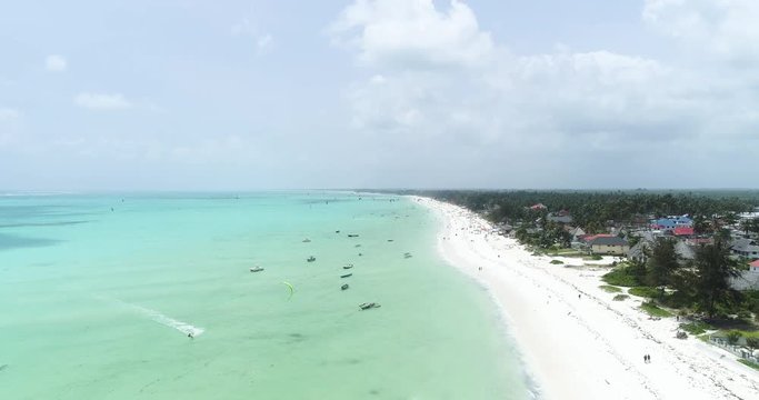 People parasail off tropical beach, aerial