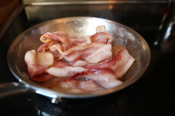 frying pan with fried bacon on the stove