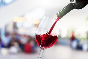 Red wine pouring in glass on  background