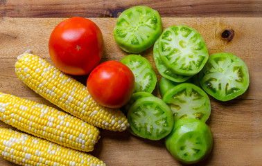 Fresh homegrown organic vegetables including corn, tomato and sliced green tomato. Ripe, juicy and delicious produce ready to prepare for a healthy satisfying nutritious meal.