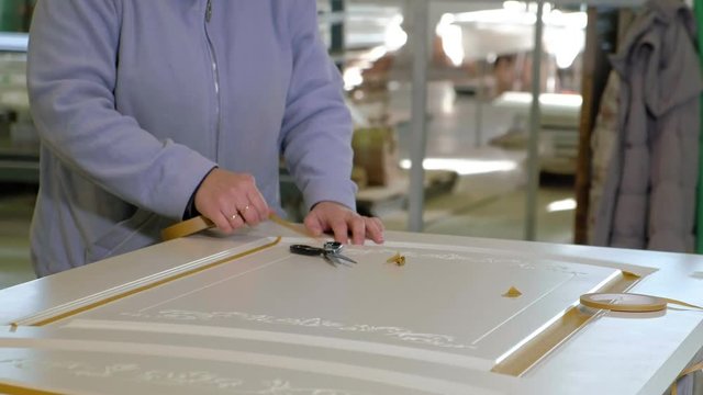 woman glues adhesive tape. production of interior doors of wood