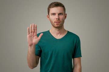 Portrait of a serious man holding hands in a stop sign, warning and preventing you from doing...