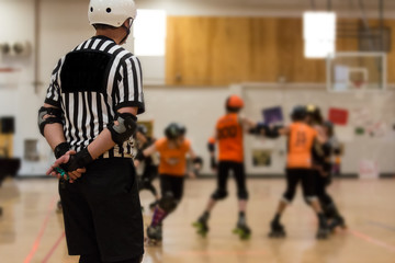 Roller derby referee watches teams for penalties
