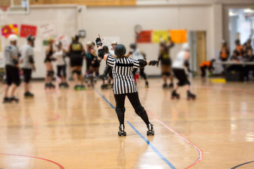 Roller derby referee watches teams for penalties