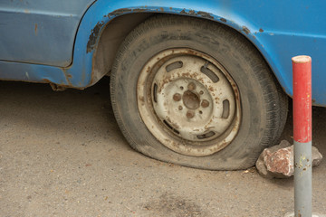 Flat rear tire on old rusty car