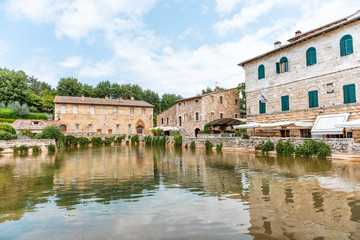 Fototapeta na wymiar Medieval town of Bagno Vignoni, San Quirico d'Orcia, Val d'Orcia, Tuscany, Italy with hot springs ruins, historical buildings, water pool reflection