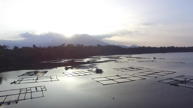 Sun rises over bamboo structure built in the middle of the lake. drone aerial shot, silhouettes