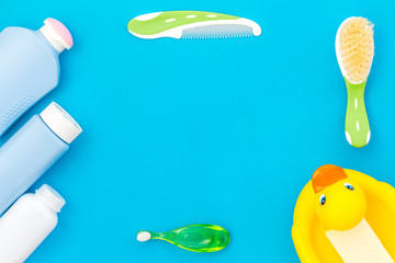 Children's personal care kit. Bath accessories with teeth brush and yellow rubber duck on blue background top view copy space