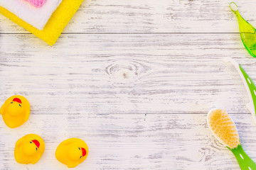 Hygiene items for the child. Bath accessories with yellow rubber duck on light grey wooden background top view copy space frame