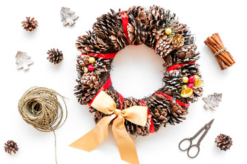 Preparing to Christmas. Christmas wreath made of pine cones near decorative elements on white background top view