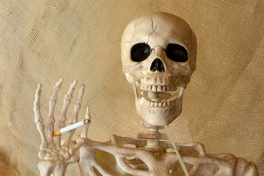 Skeleton holding lit cigarette with hand and canula for oxygen attached to nasal cavity
