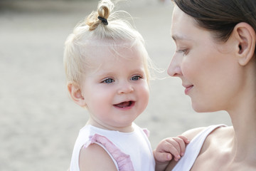
Outdoor portrait of young mother holding an adorable baby girl, natural light candid shoot