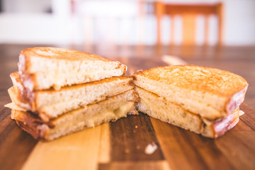 Hot cut toasted cheese sandwiches on a wooden cutting board. Sourdough bread.