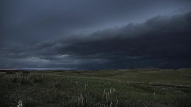 Lighting flashing over the landscape as storm rolls through valley at dusk.