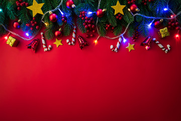 Christmas background concept. Top view of Christmas gift box red sock with spruce branches, pine cones, red berries and bell on red background.