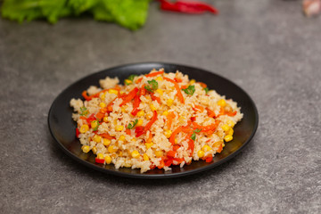 Chinese fried rice with vegetables, served on a plate with chopsticks. Selective focus