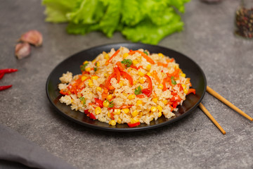 Chinese fried rice with vegetables, served on a plate with chopsticks. Selective focus