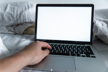 man working in bed on laptop. white screen