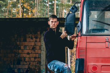 Portrait of young man stand on side on truck cabin
