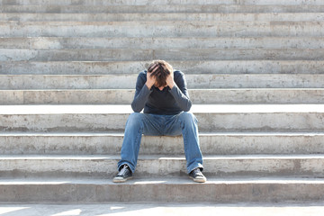 Man sitting on the stairs is saddened and frustrated with life. Concept. Toned photo.
