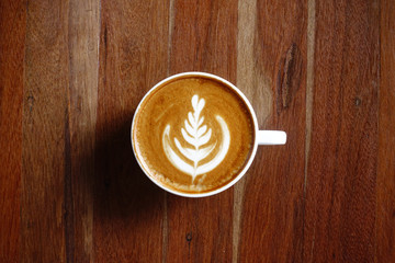 a cup of latte art coffee on wooden background