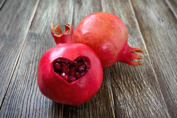 Ripe pomegranate fruit close up on wooden background. Healthy eating concept. Cut in the shape of a...