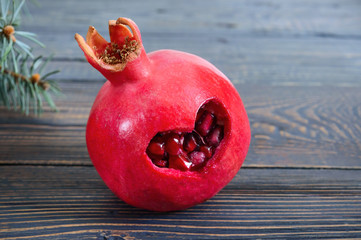 Ripe pomegranate fruit close up on wooden background. Healthy eating concept. Cut in the shape of a...
