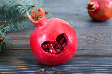 Ripe pomegranate fruit close up on wooden background. Healthy eating concept. Cut in the shape of a heart on the pomegranate skin.